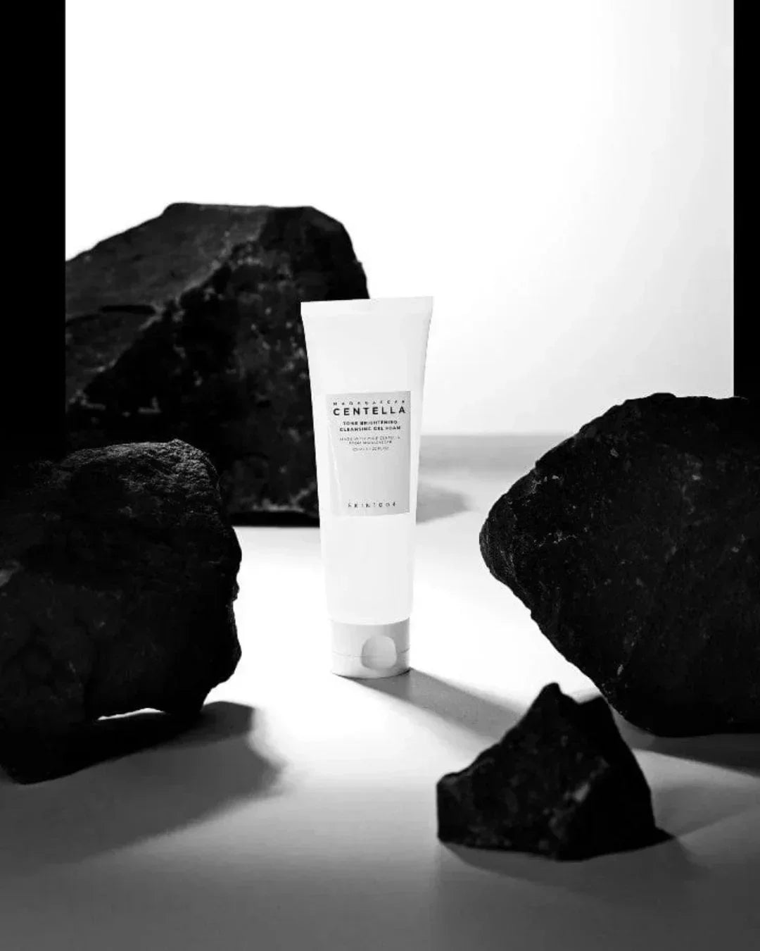 Madagascar Centella Tone Brightening Cleansing Gel Foam tube surrounded by black volcanic rocks