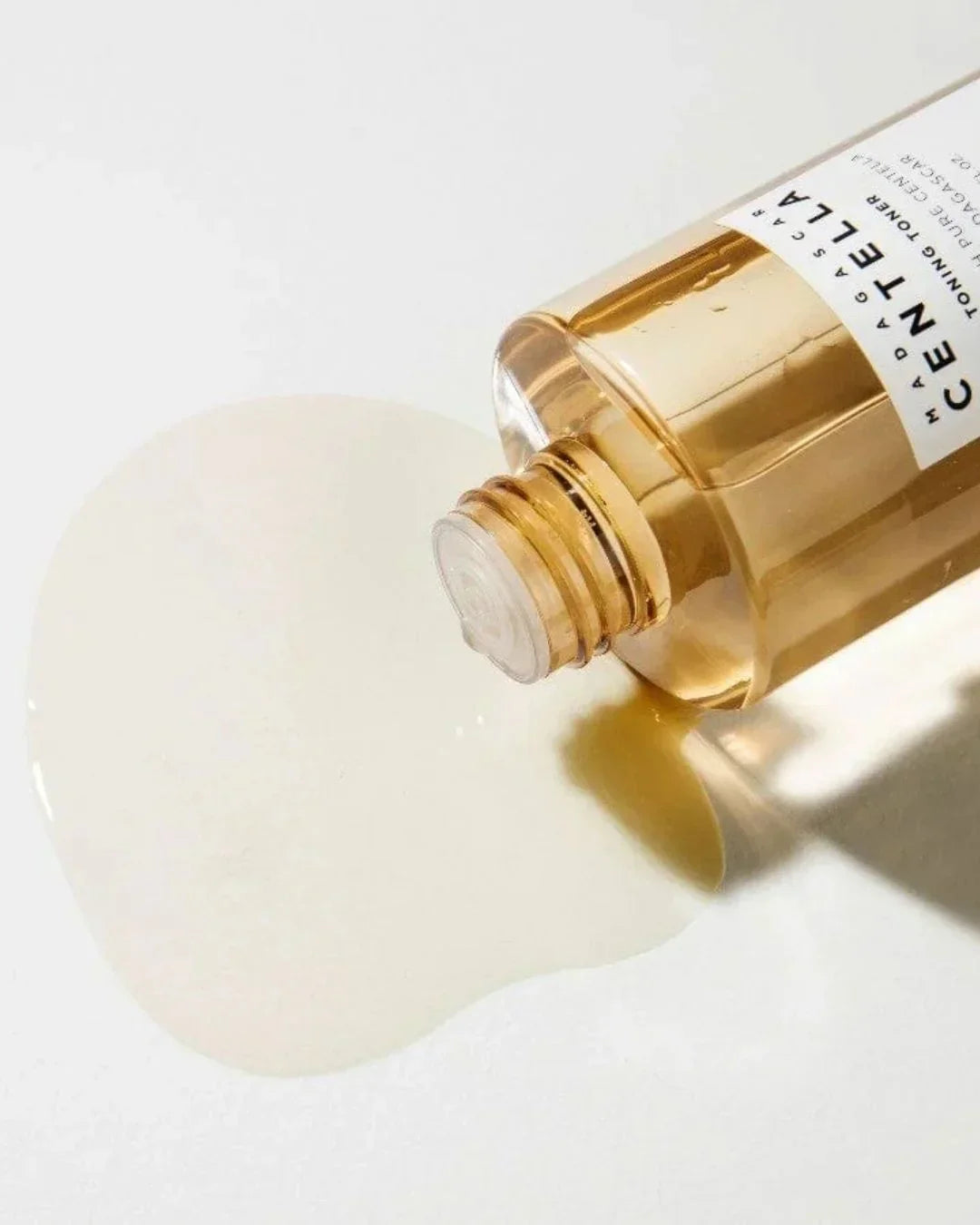 Madagascar Centella toning toner bottle lying on white surface with spilled liquid.