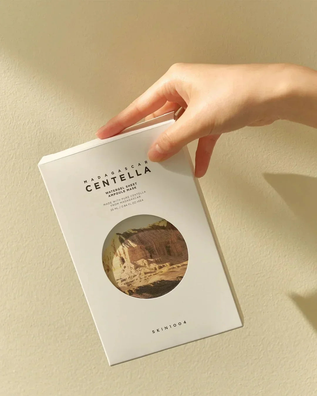 Hand holding Madagascar Centella Watergel Sheet Ampoule Mask box with natural light and shadow