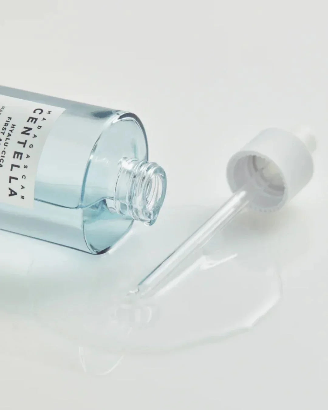 Madagascar Centella Hyalu-Cica First Ampoule skincare serum with dropper and spilled liquid on white surface