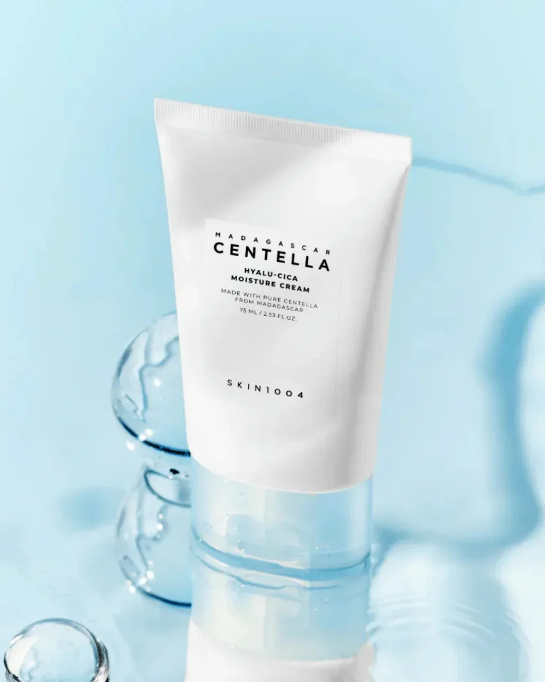 White tube of Madagascar Centella Hyalu-Cica moisture cream by SKIN1004 on blue background with water droplets