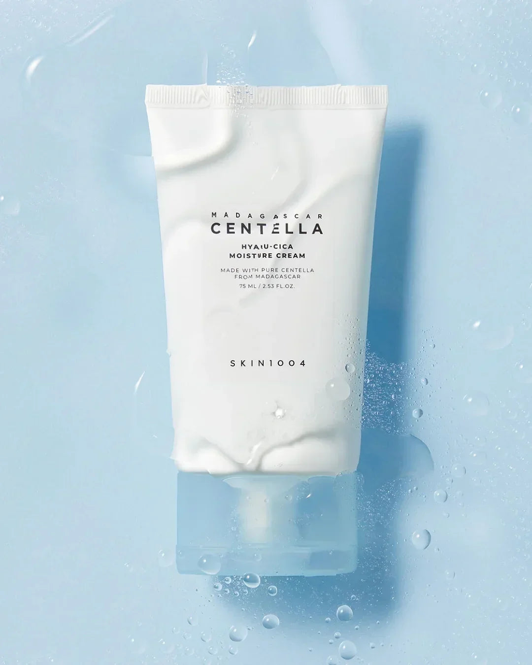 Skin1004 Madagascar Centella Hyalu-Cica Moisture Cream 75ml tube on blue wet surface with water droplets