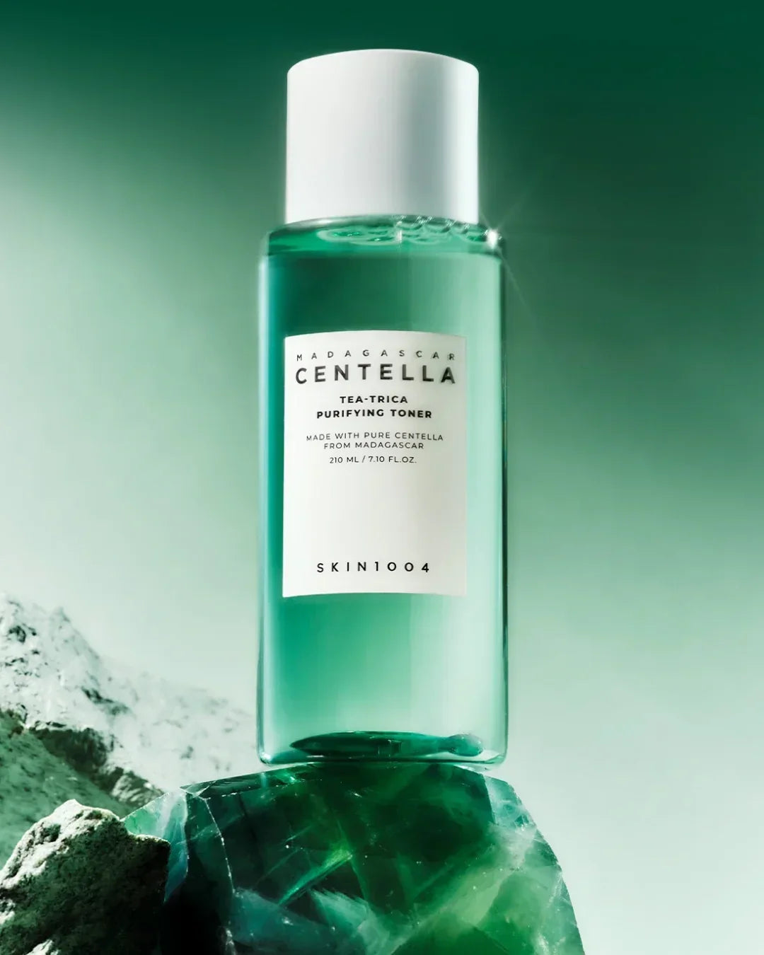 Madagascar Centella Tea-Trica Purifying Toner bottle on a green crystal with green gradient background