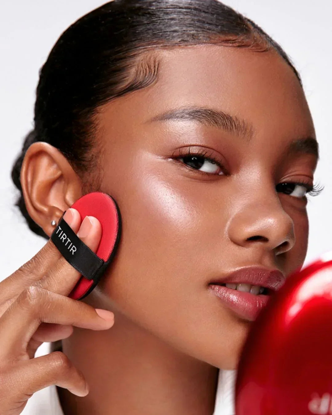 Close-up of woman applying makeup with red TIRTIR cushion puff for flawless skin