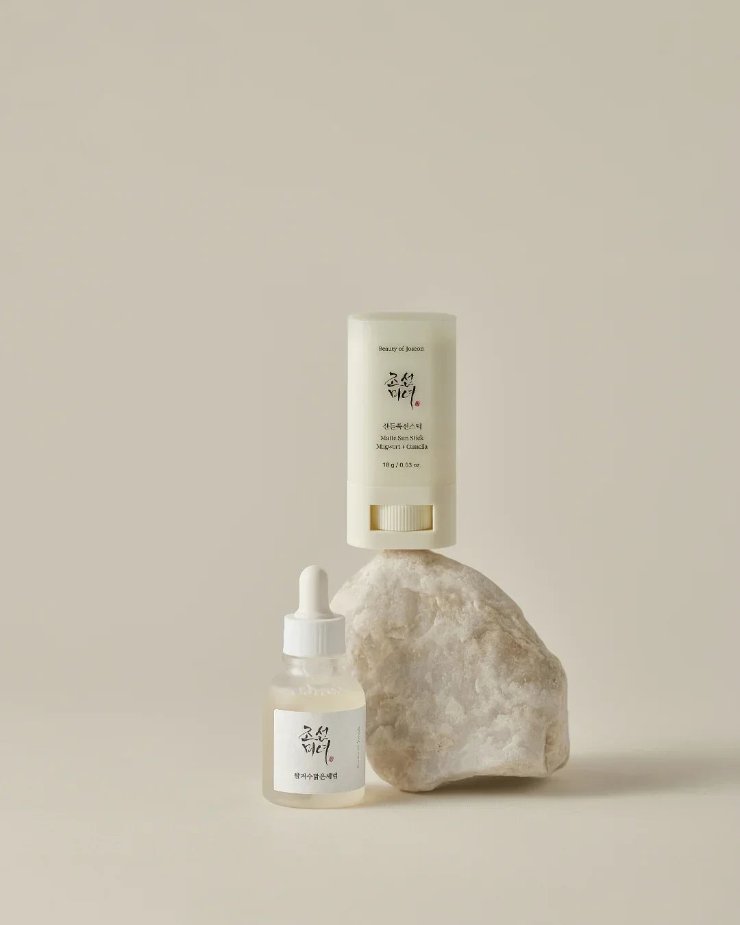 Matte Sun Stick with Mugwort and Camellia and dropper bottle skincare products on a natural stone
