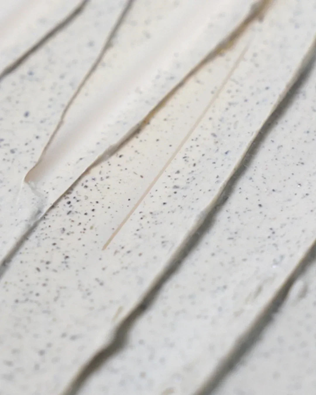 Close-up texture of mugwort calming clay mask with smooth beige cream and speckled particles