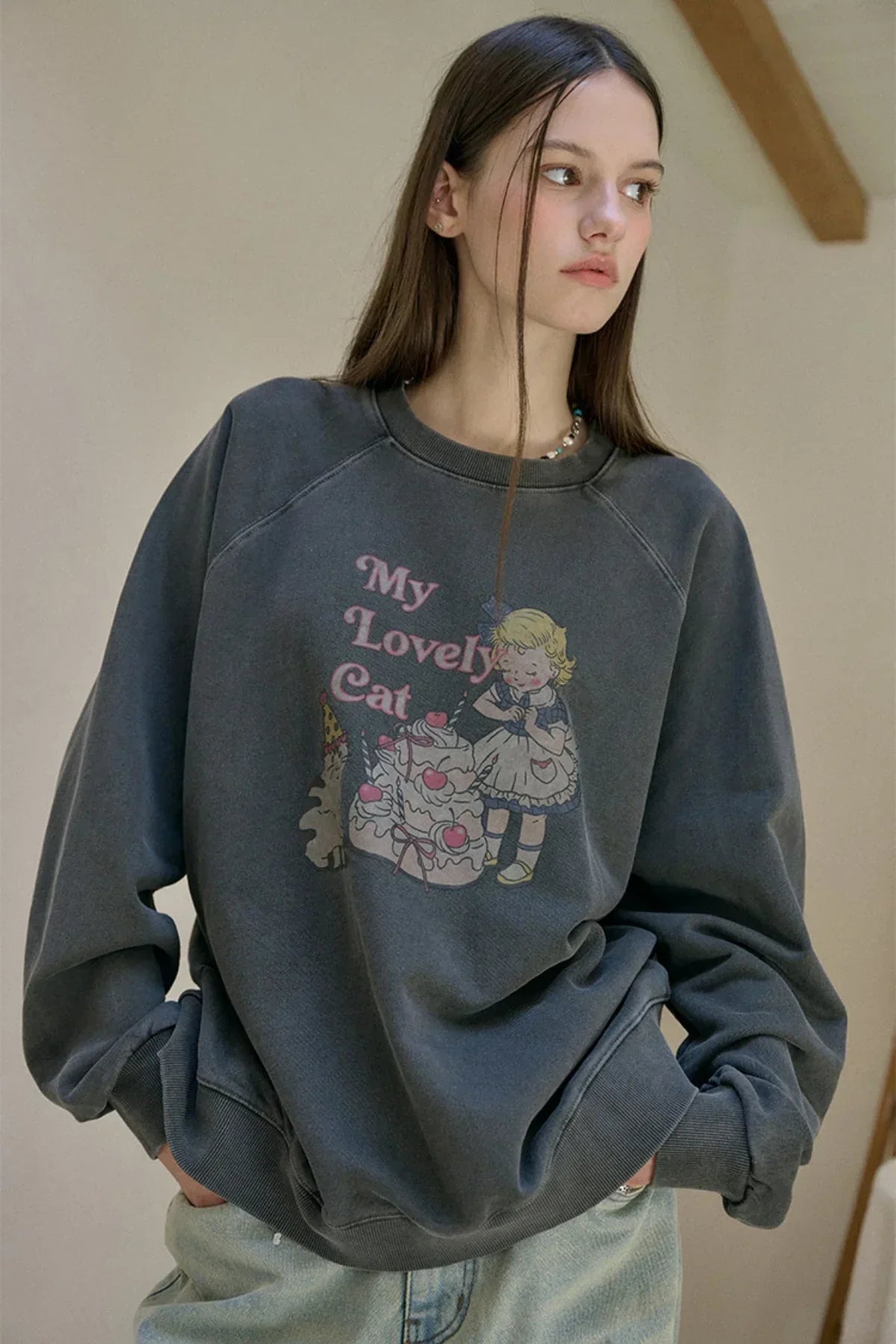 Close-up of woman wearing smoke black raglan sweatshirt with My Lovely Cat graphic and light jeans