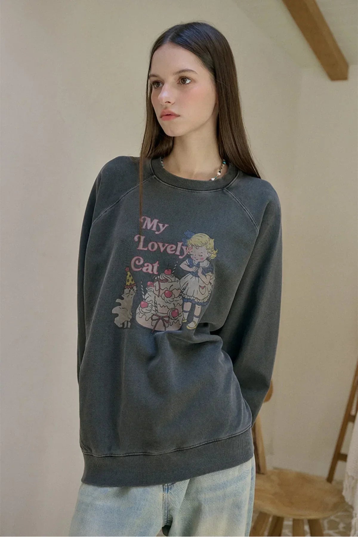 woman wearing smoke black sweatshirt with vintage 'My Lovely Cat' print and light blue jeans indoors