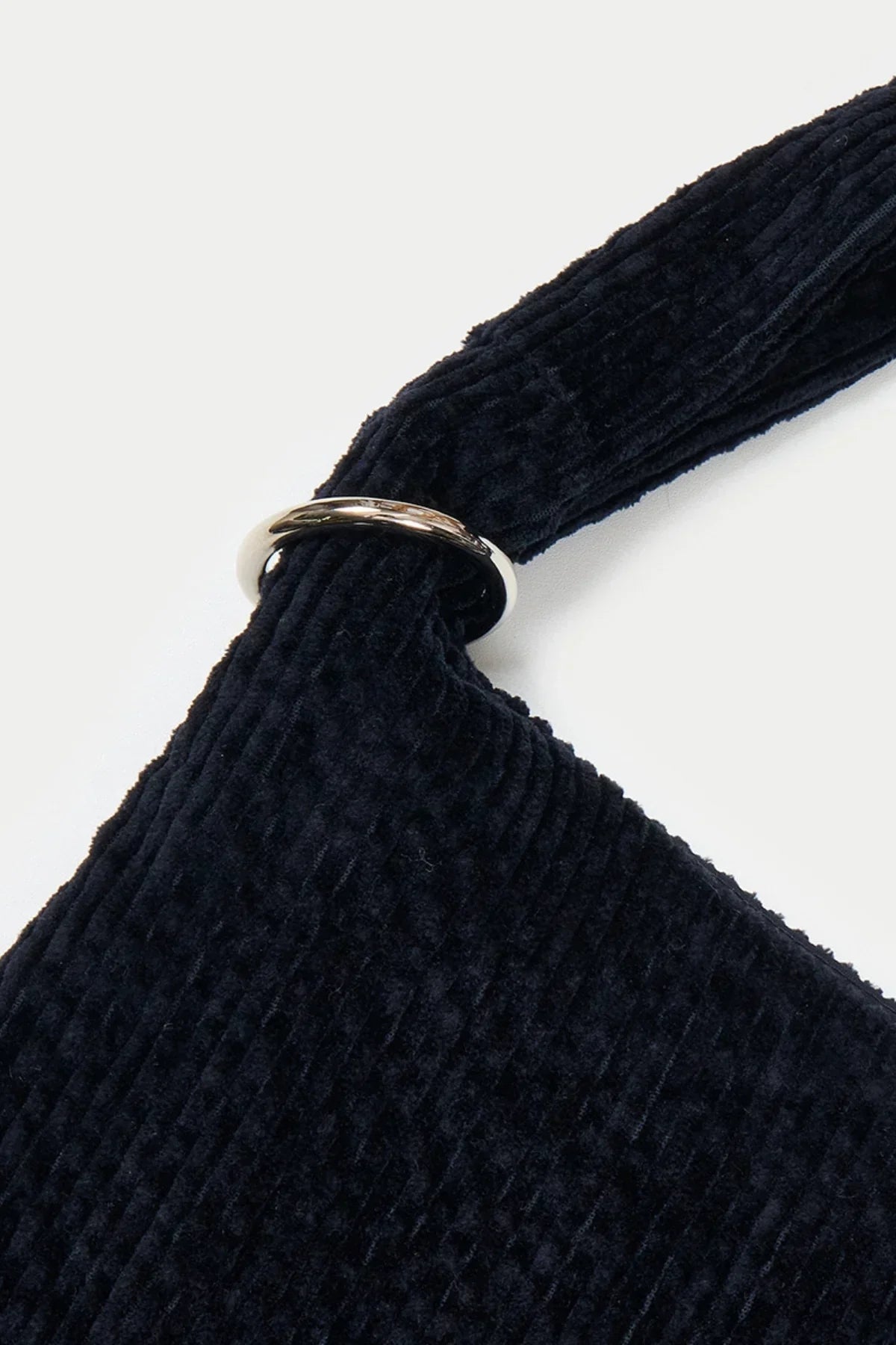 Close-up of dark navy blue corduroy fabric with a silver metal ring detail