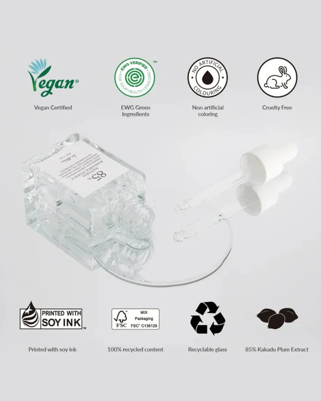 Clear essence bottle with dropper on white surface displaying vegan, cruelty free, EWG green ingredients, recyclable glass icons