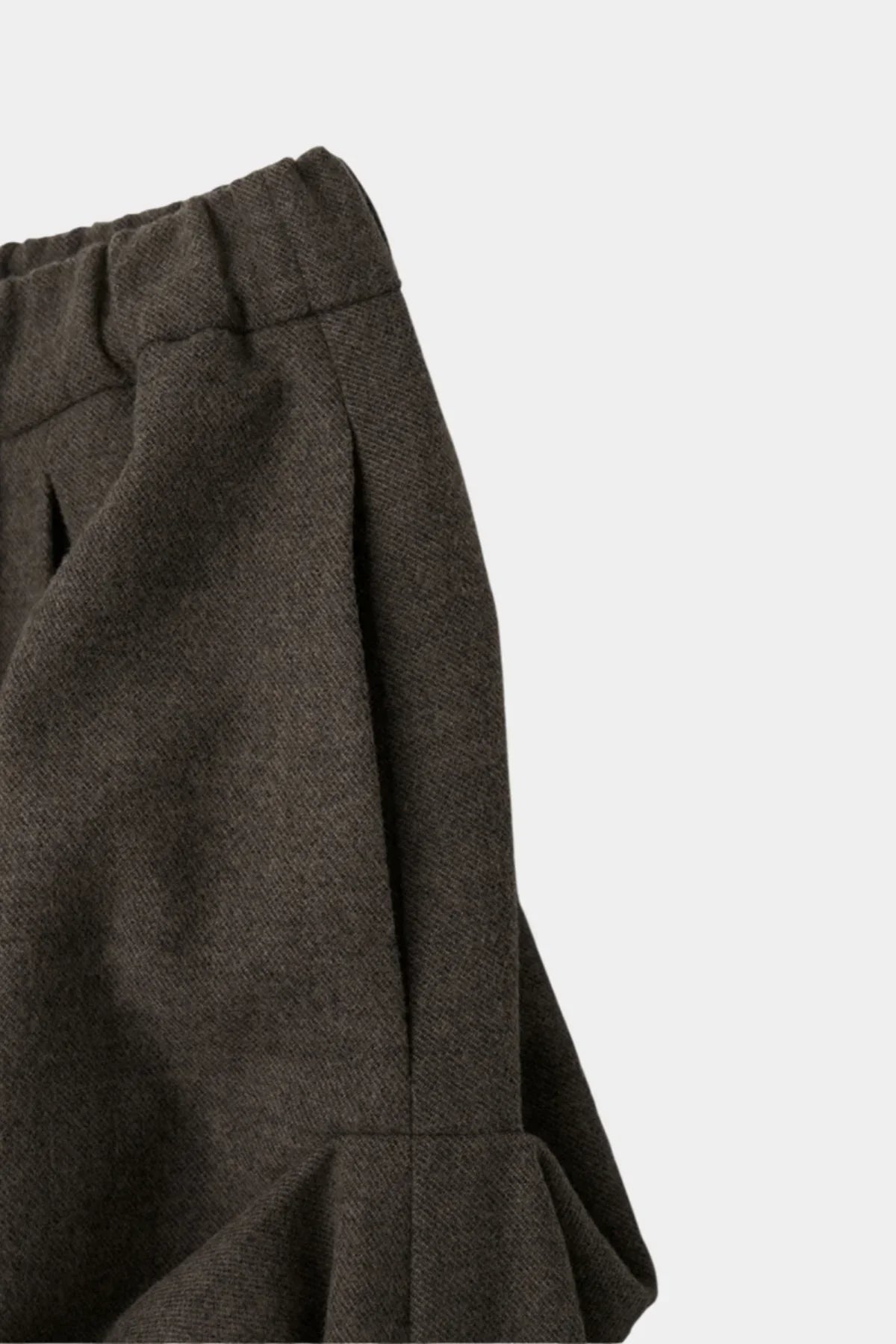 Close-up of brown fabric skirt with elastic waistband and pleated design detail