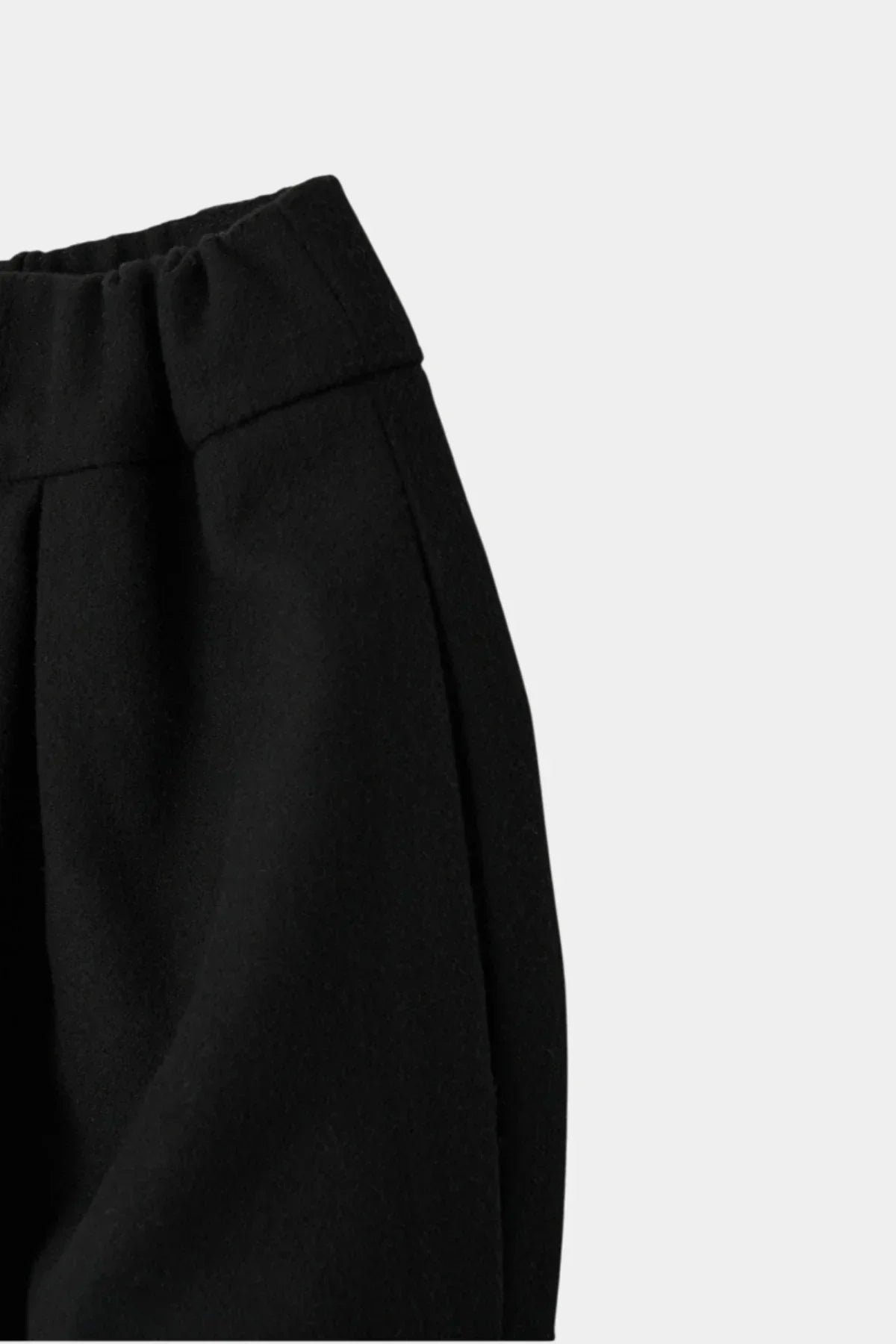 Close-up of black skirt fabric with elastic waistband and pleated detail