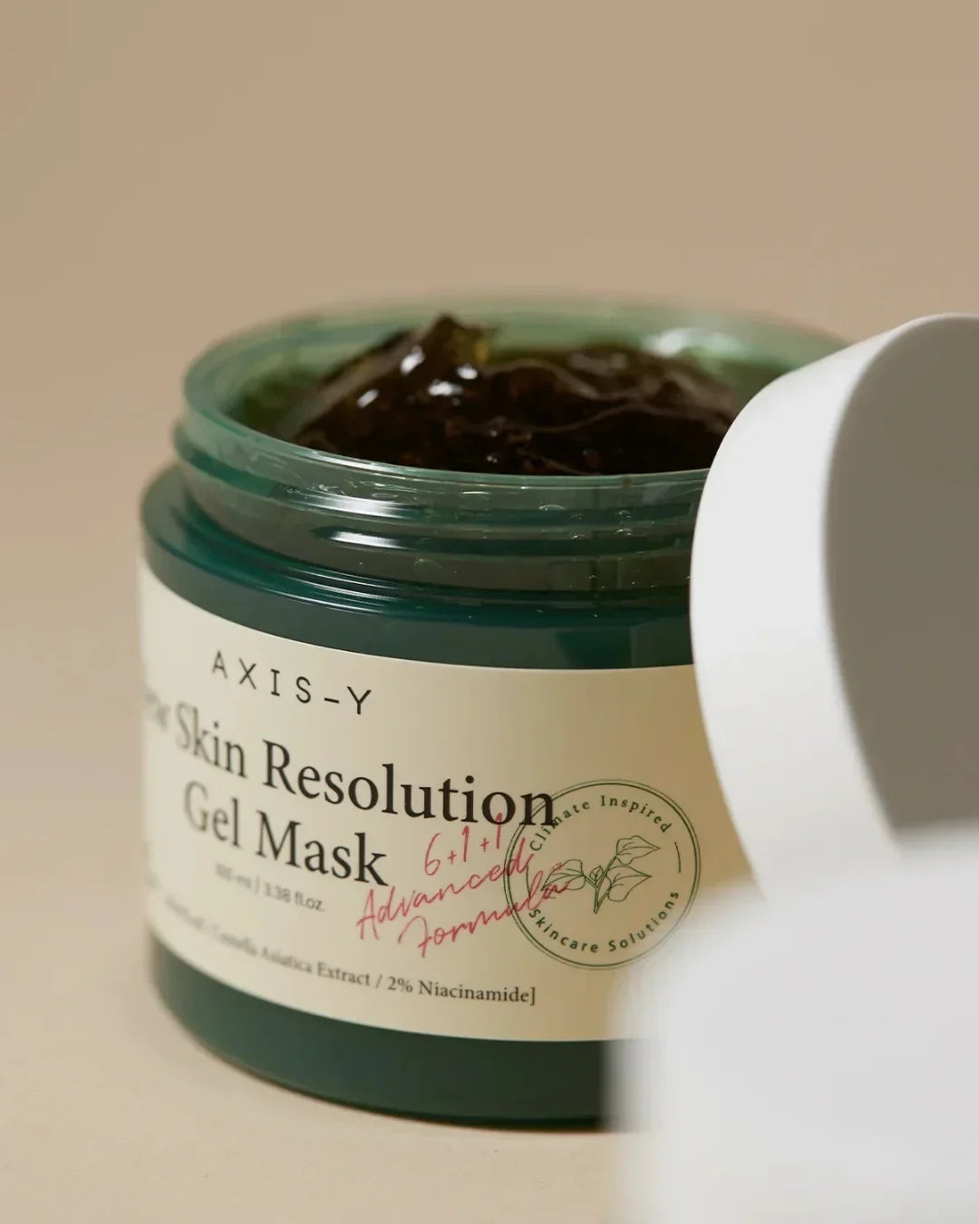 Open jar of Axis-Y Dark Skin Resolution Gel Mask with visible dark gel and white lid on beige background