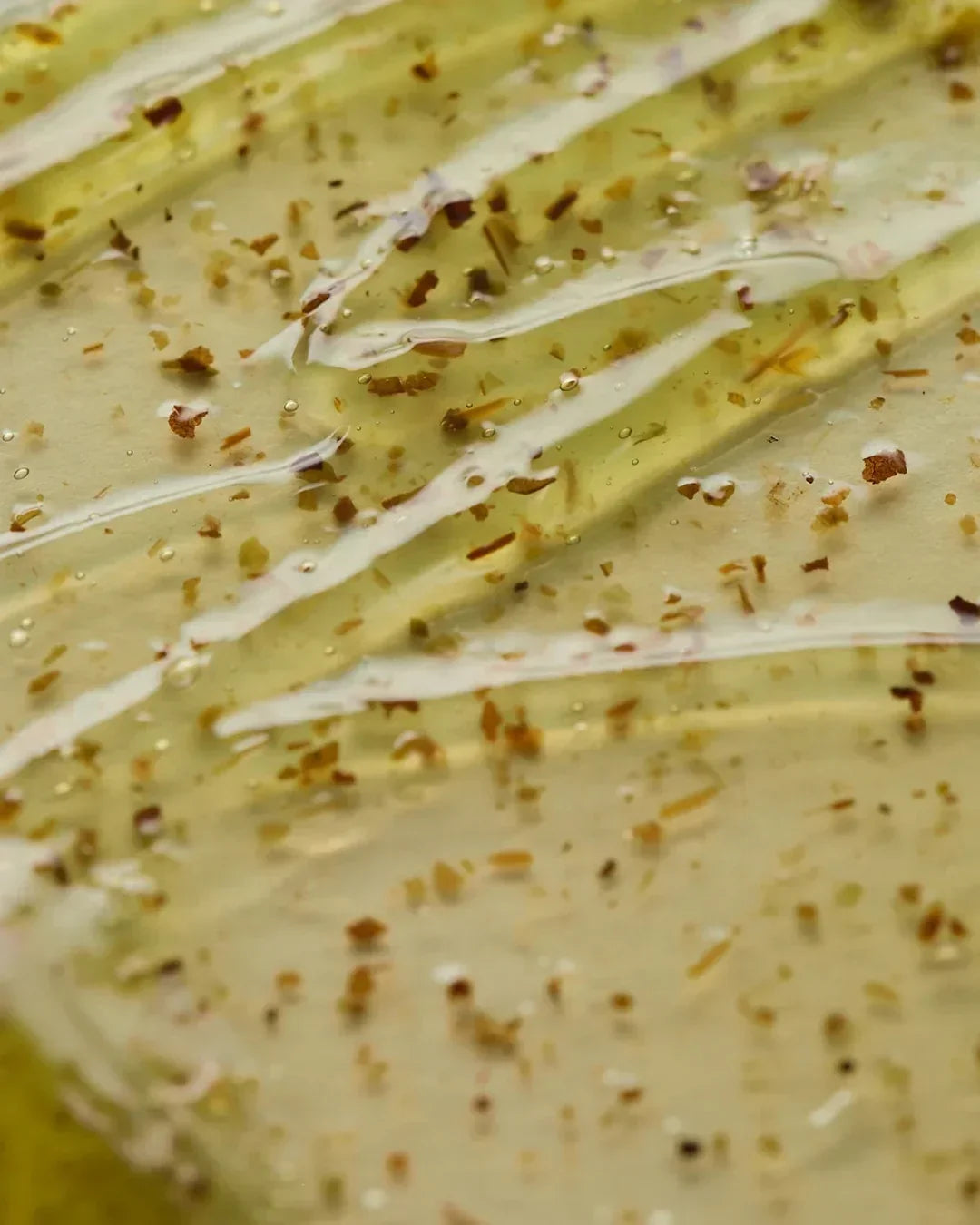 Close-up of clear gel texture with natural plant flakes and bubbles, skincare mask detail
