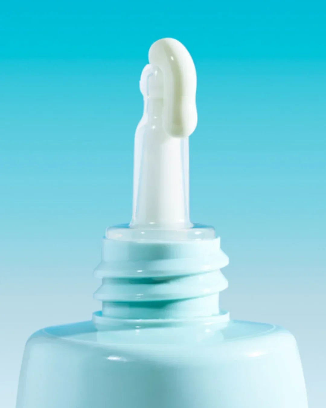 Close-up of light blue sunscreen tube with white cream on tip against blue gradient background