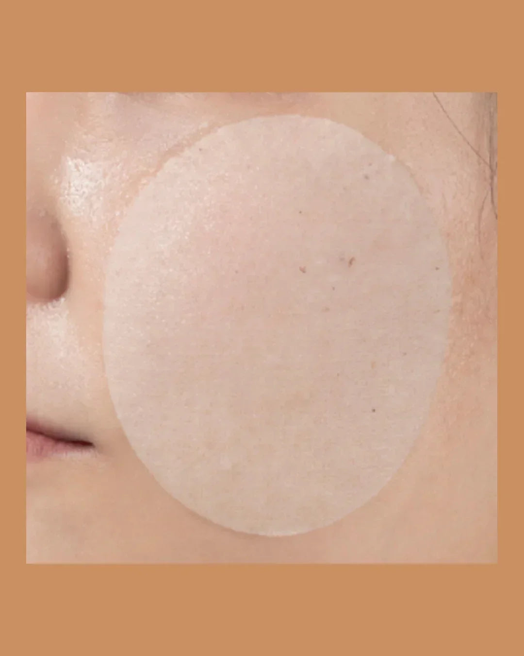 Close-up of cheek with translucent cosmetic essence pad applied on skin