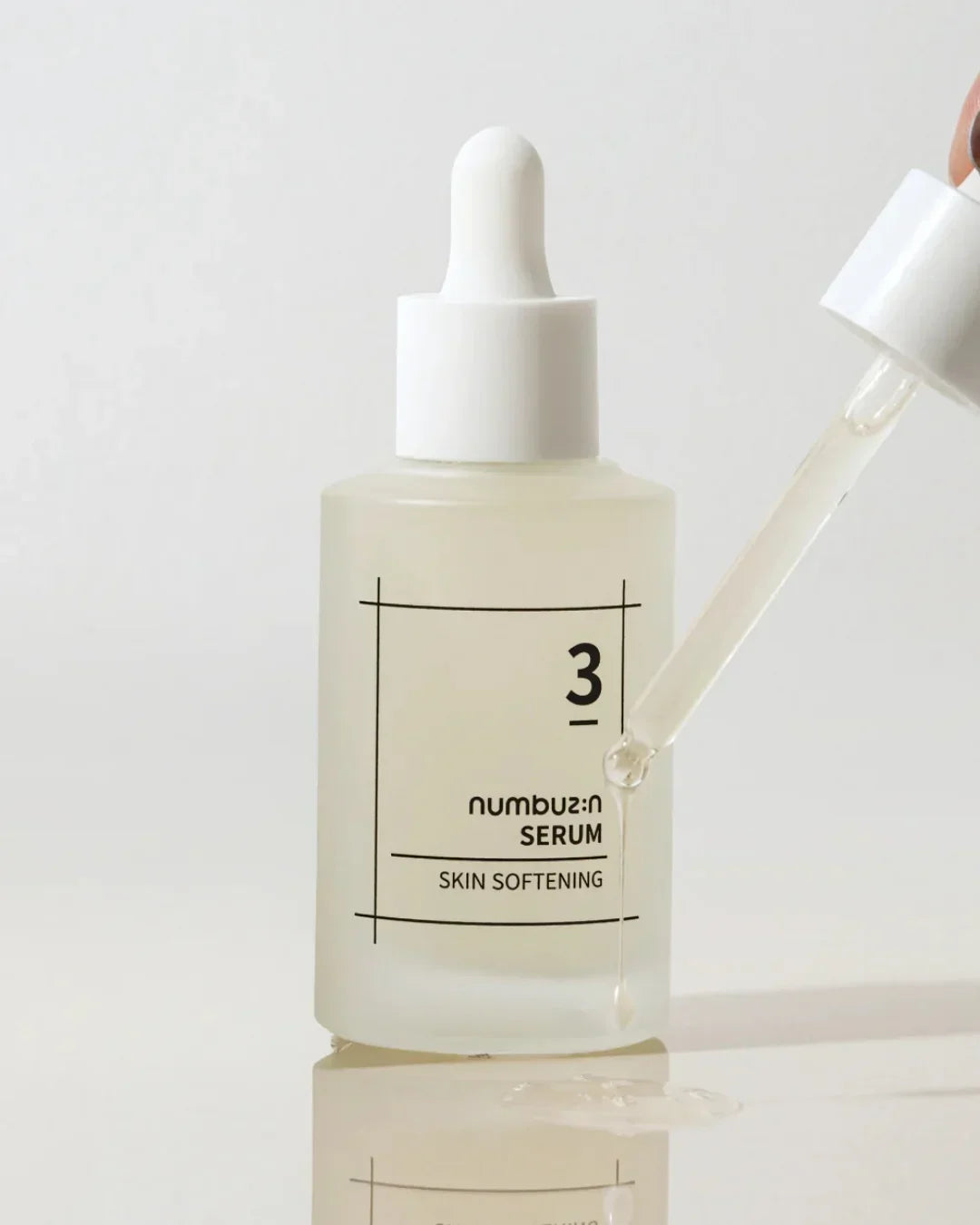 Numbuz:n No3 skin softening serum bottle with dropper dispensing clear liquid on white surface