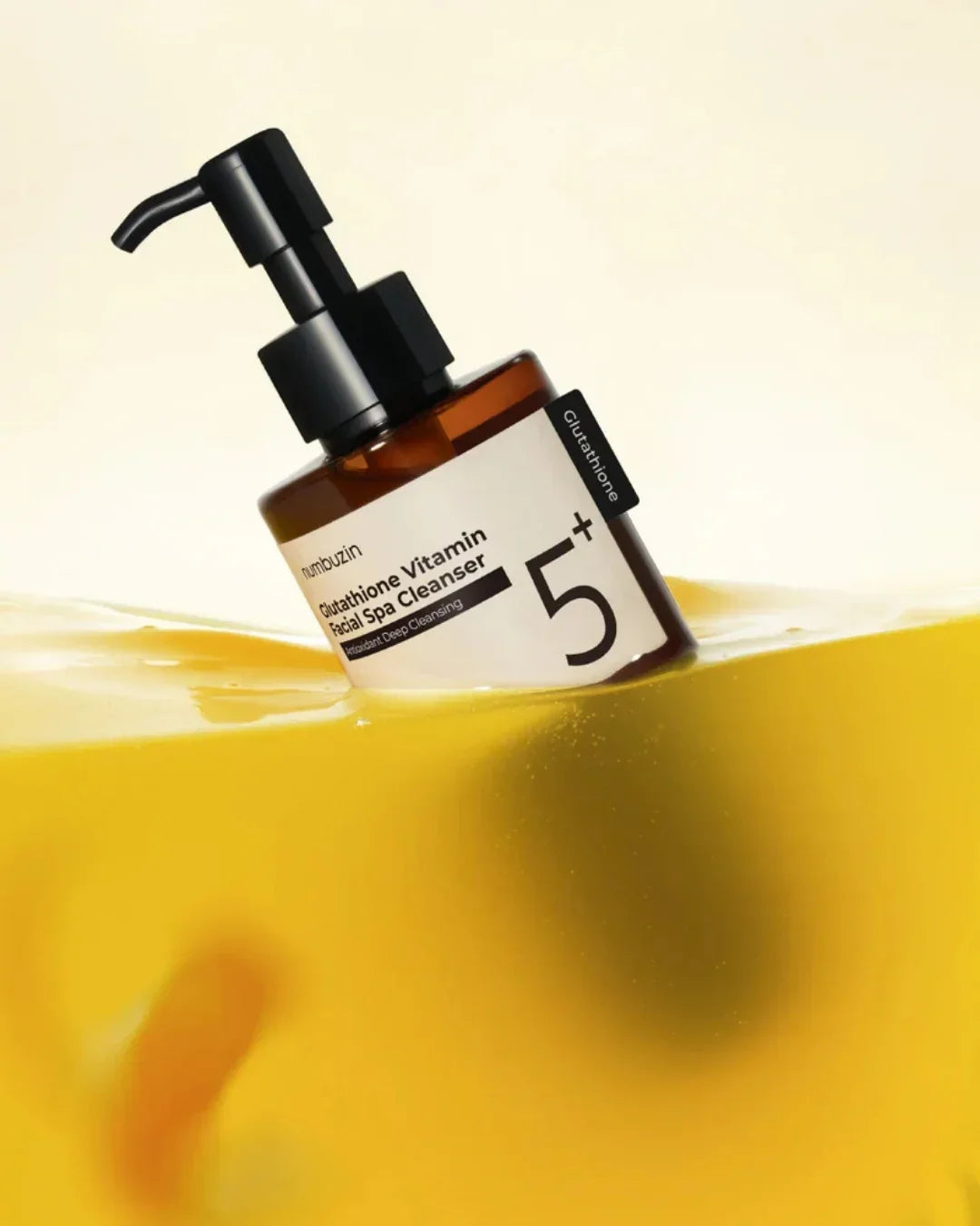 Pump bottle of Glutathione Vitamin Facial Spa Cleanser partially submerged in yellow liquid