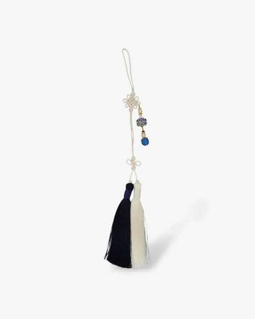 Blue and white traditional Korean norigae tassel with floral charm on white background