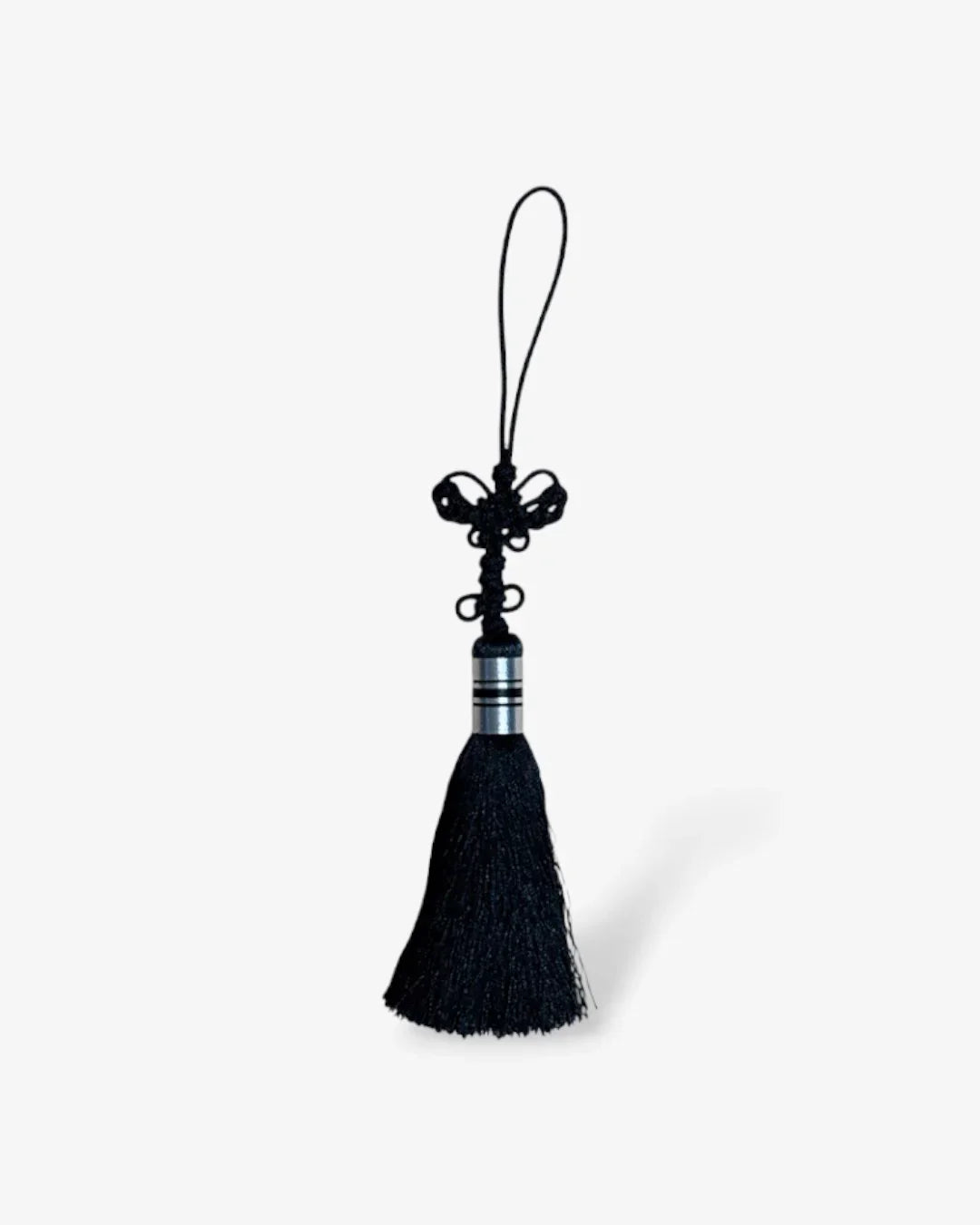 Black norigae tassel with decorative knot and silver metal detailing on white background