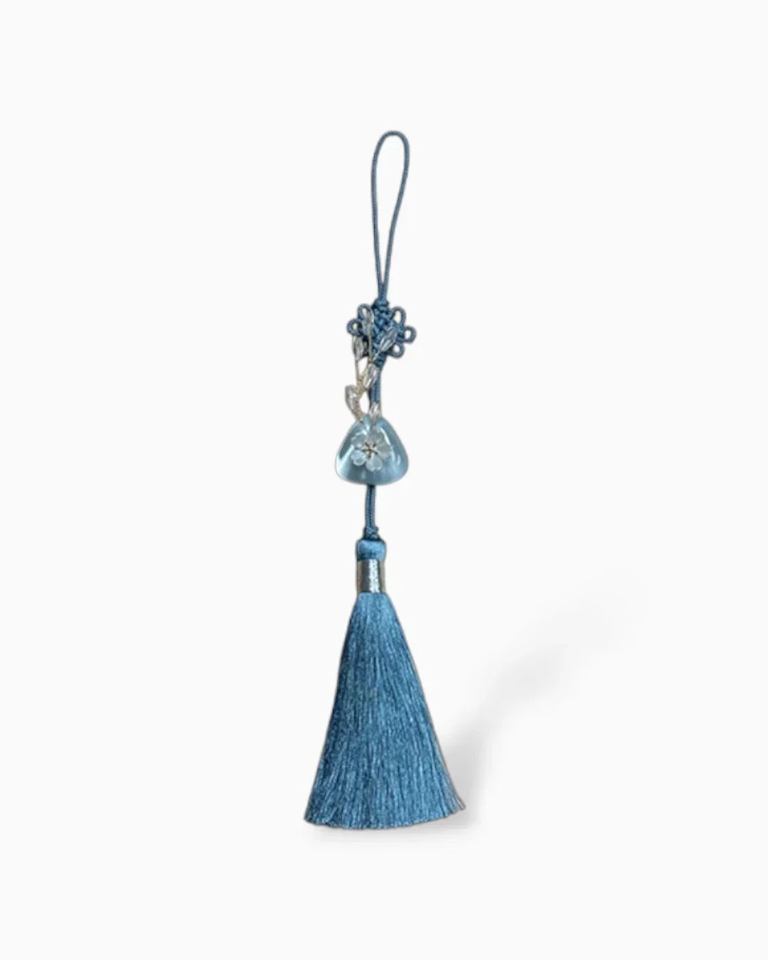 Blue norigae keychain with tassel and floral glass bead detail on white background