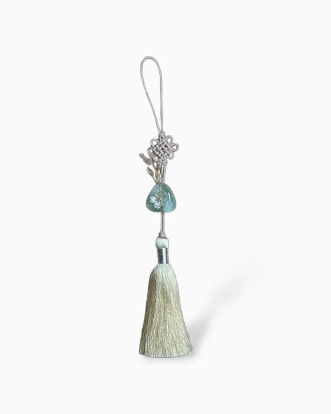 Light yellow Korean norigae tassel with decorative knot and green ornament on white background