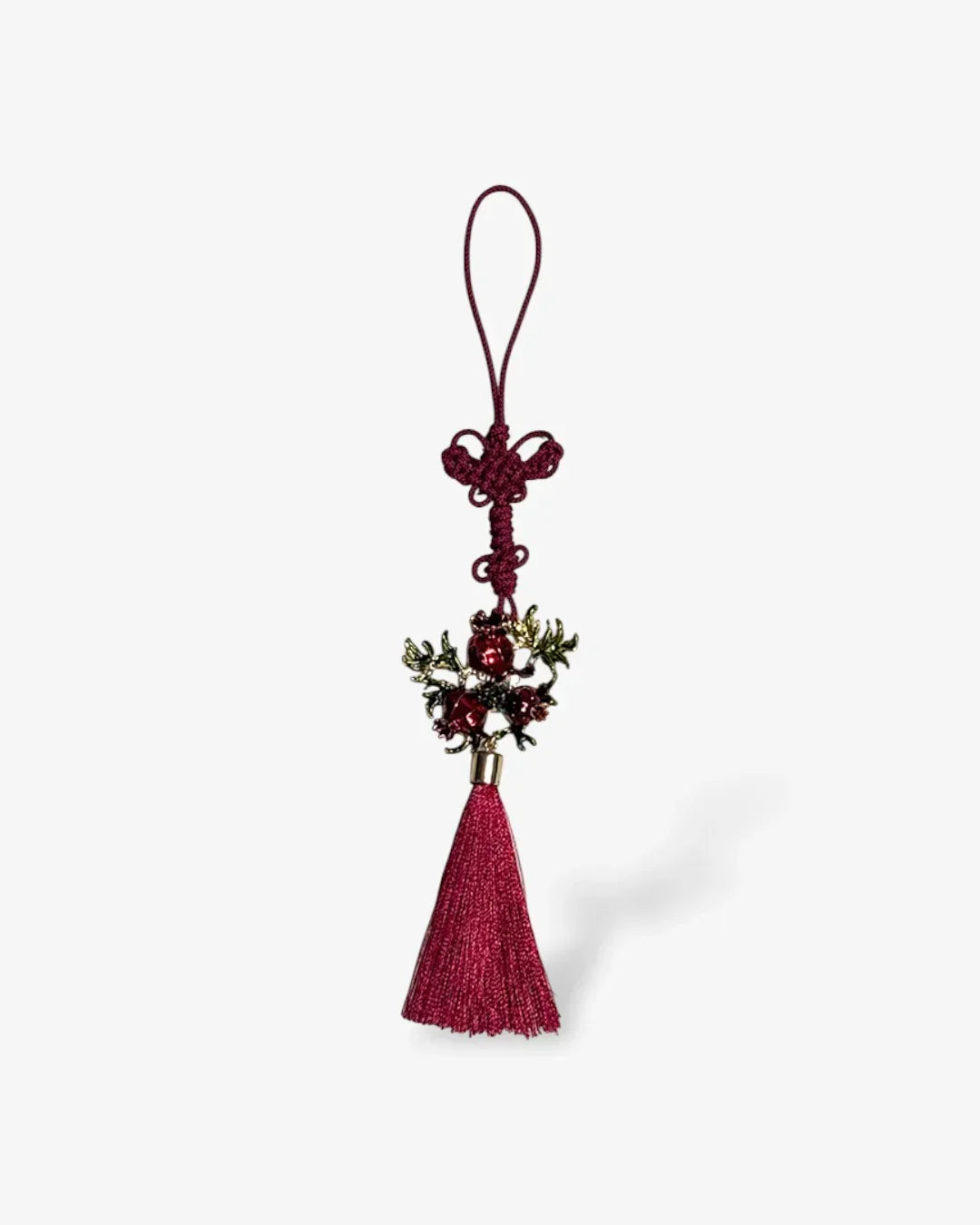 Maroon tassel norigae with decorative pomegranate charm and knotted loop on white background