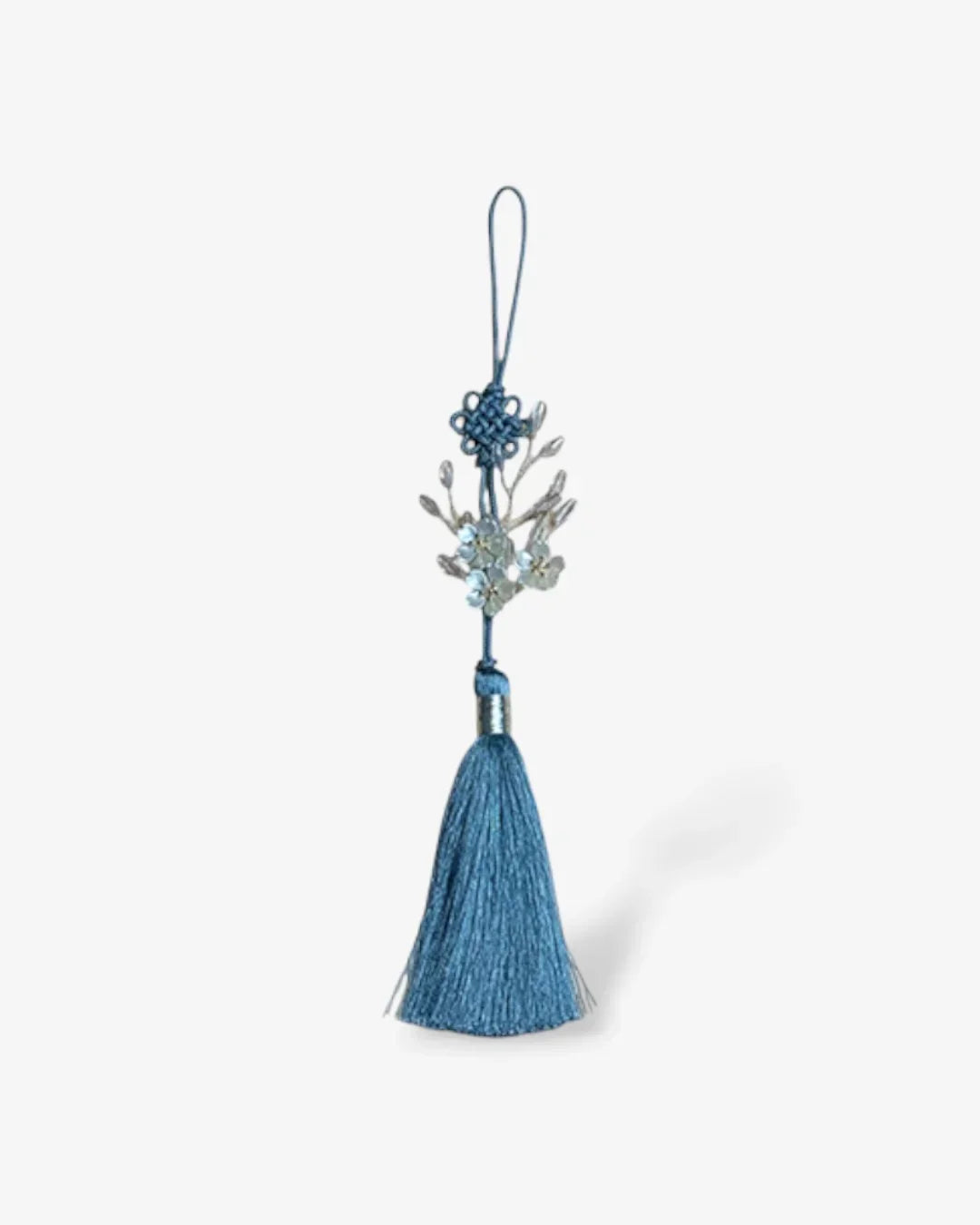 Blue traditional norigae tassel with small delicate floral ornament on white background