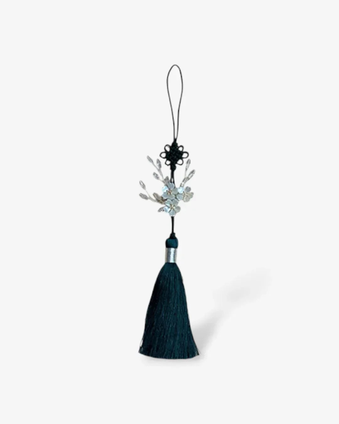 Dark green silk tassel with silver floral ornaments and traditional knot hanging on white background