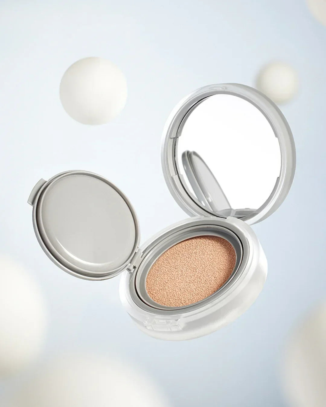 Open cushion compact foundation with beige textured sponge and built-in mirror on light background