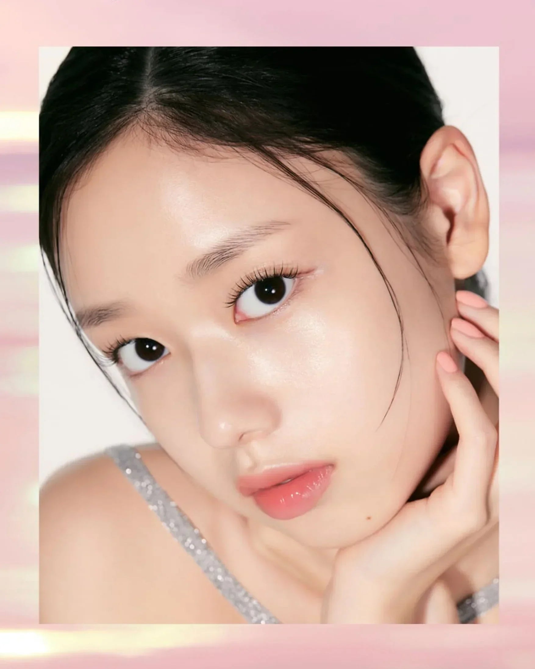 Close-up of a young woman with clear skin, glossy lips, and manicured nails in a silver top