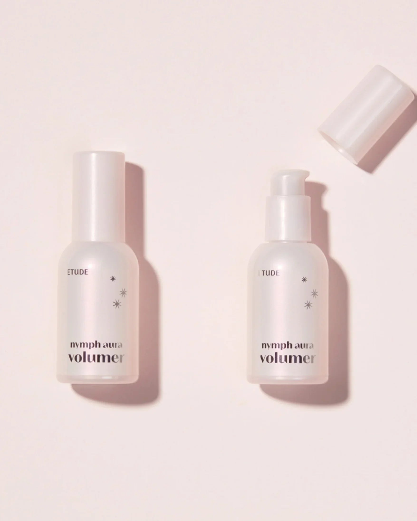 Two Etude Nymph Aura Volumer skincare bottles on a light pink background, one with cap off