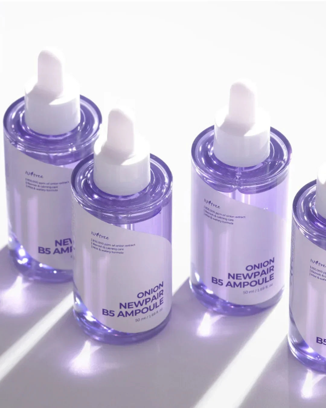 Four transparent purple bottles of Isntree Onion Newpair B5 Ampoule with white droppers on white surface