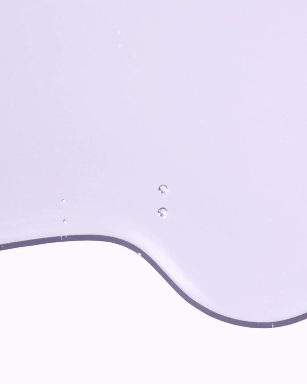 Close-up of translucent skincare ampoule texture with droplets on pale purple background
