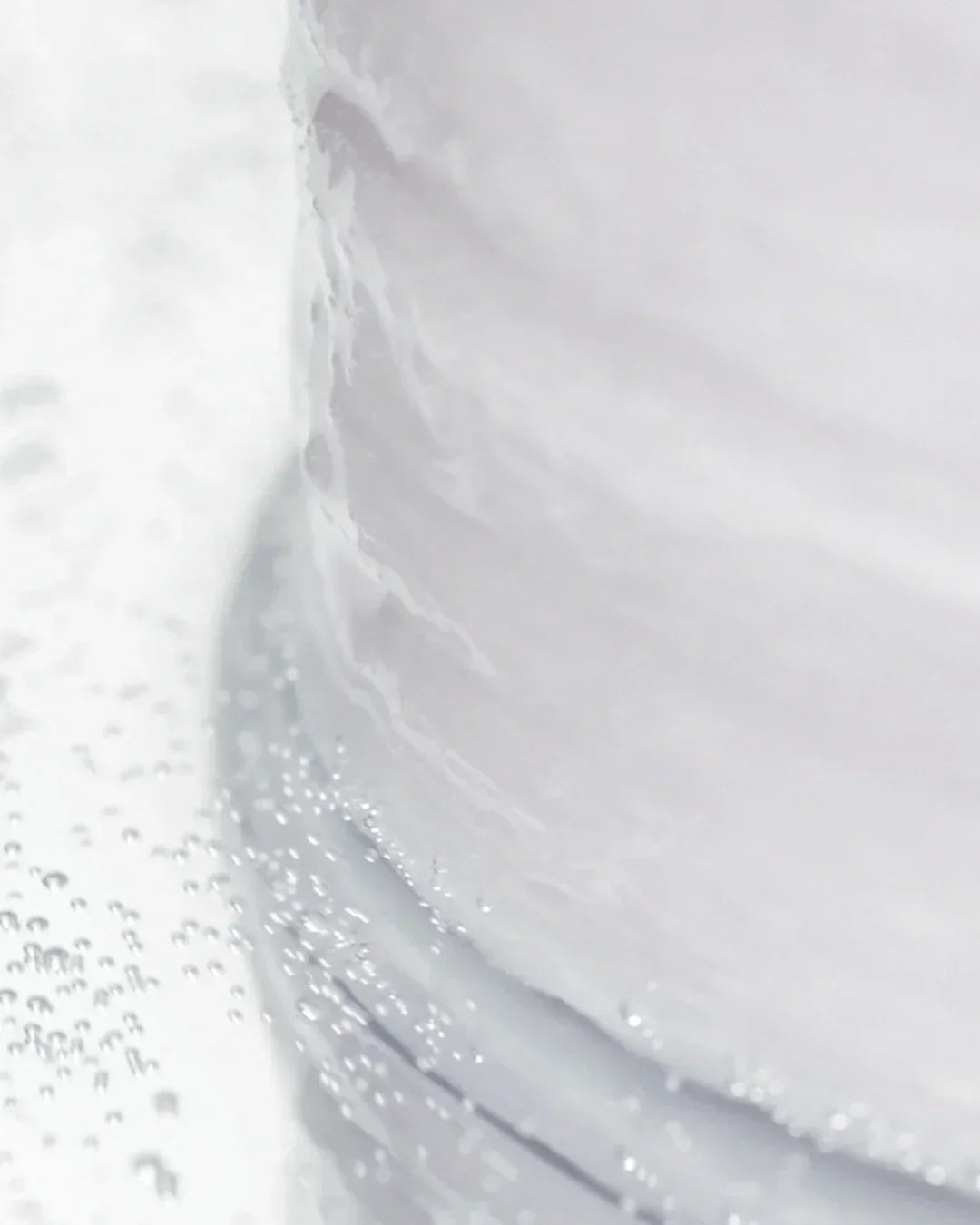 Close-up of a translucent liquid with tiny bubbles around the base of a container in soft lighting