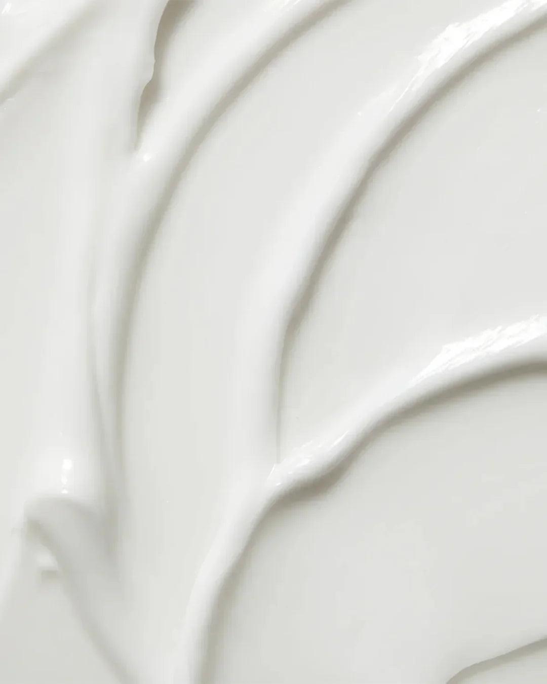 Smooth white cream texture swirled on a flat surface, representing skincare moisturizer