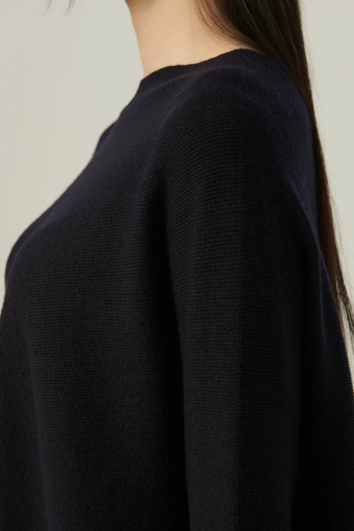 Close-up of navy blue parachute line knit pullover worn by person with long dark hair