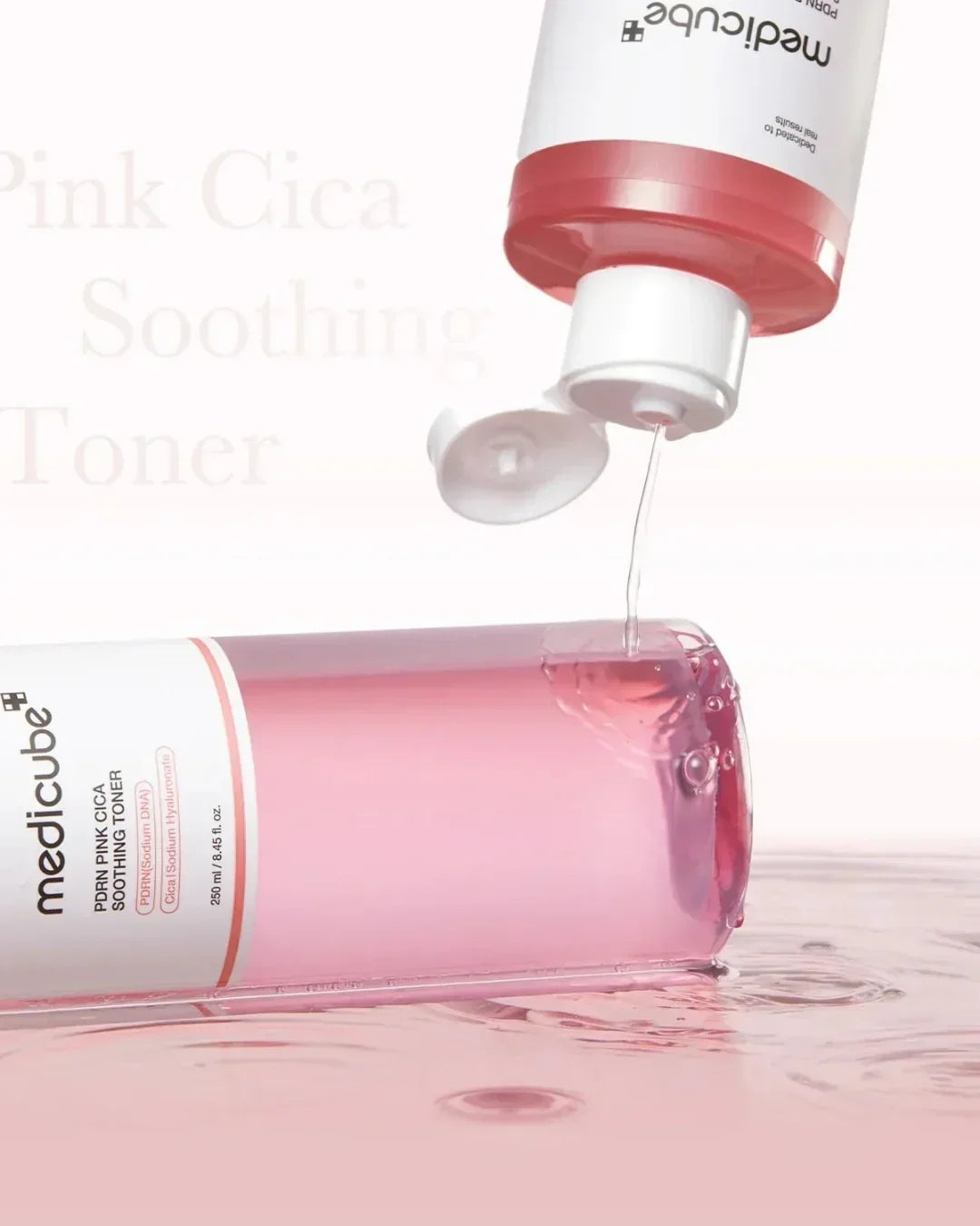 MediCube Pink Cica Soothing Toner pouring liquid onto pink reflective surface