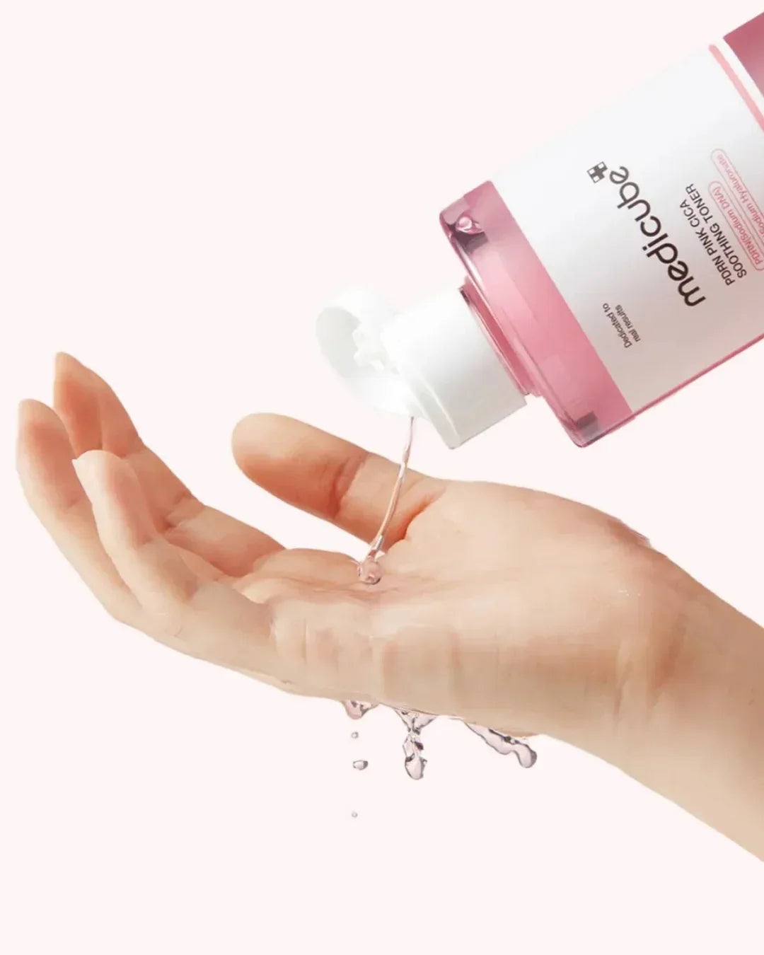 Pouring Medicube PDRN Pink Cica Soothing Toner onto hand with pink liquid dripping