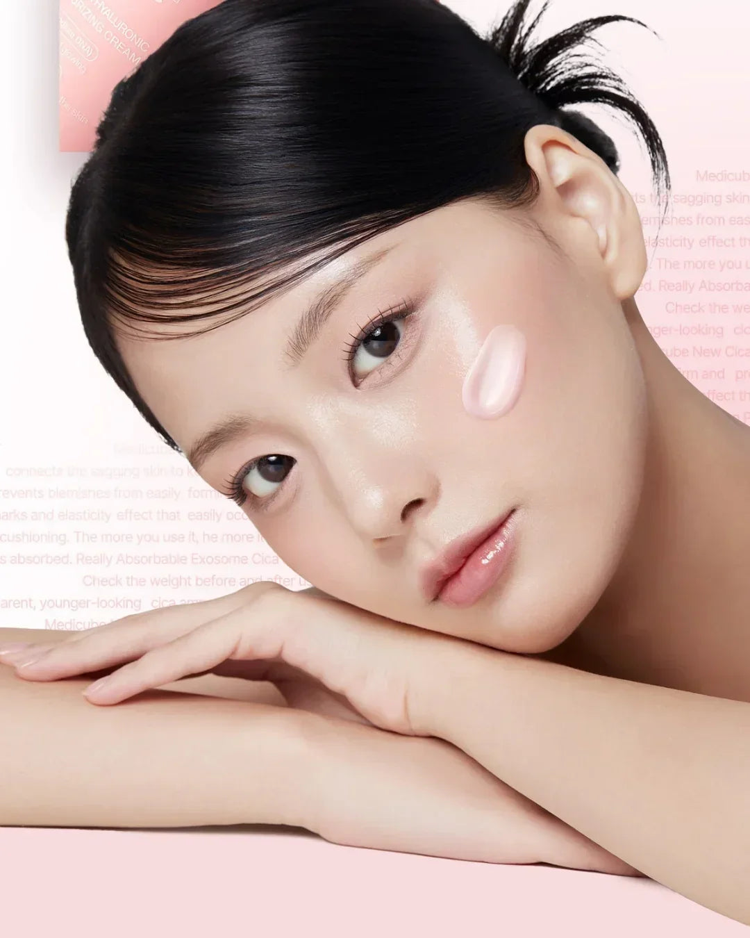 Close-up of woman with clear skin applying pink hyaluronic moisturizing cream on cheek