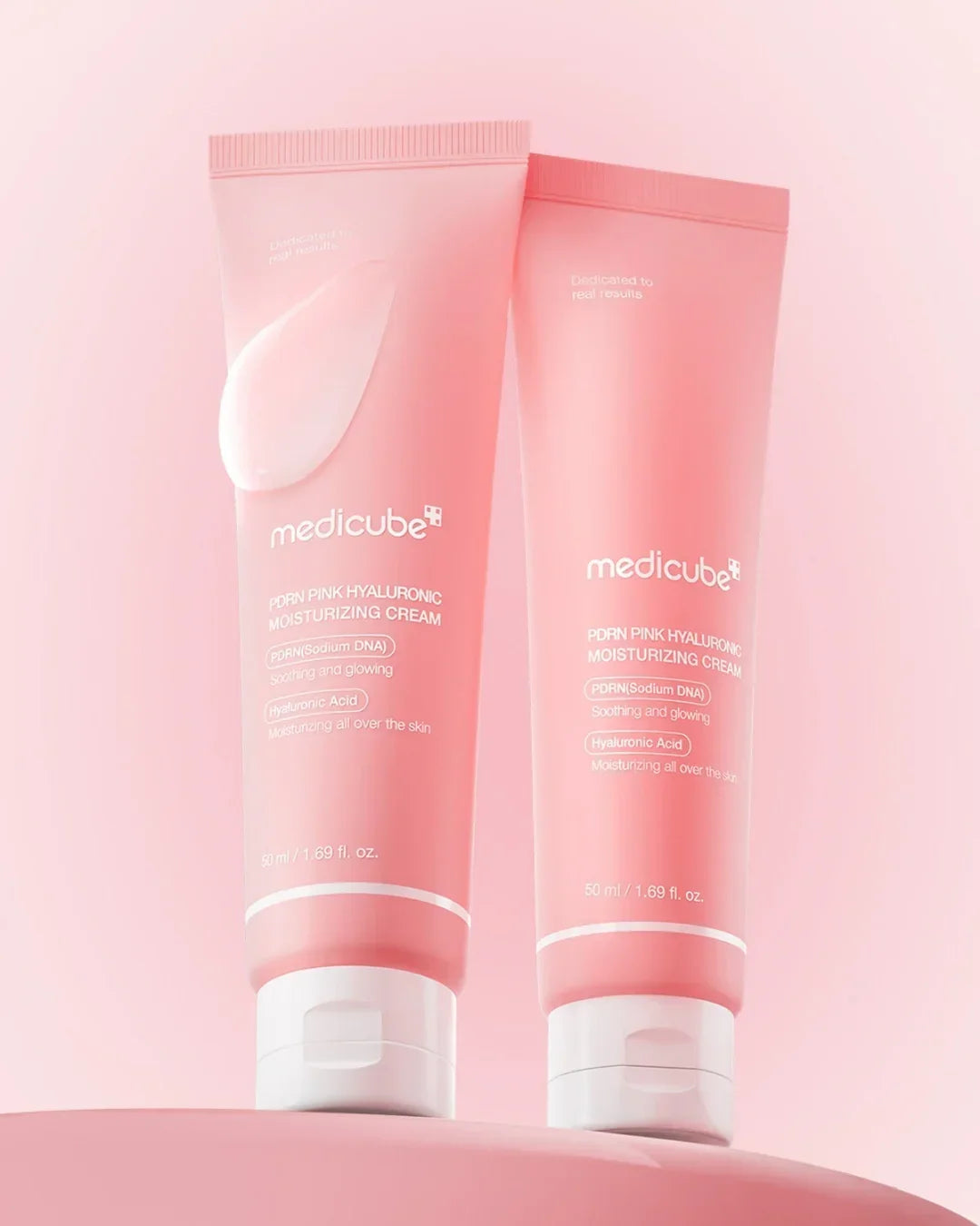 Two pink tubes of Medicube PDRN Pink Hyaluronic Moisturizing Cream on a pink background