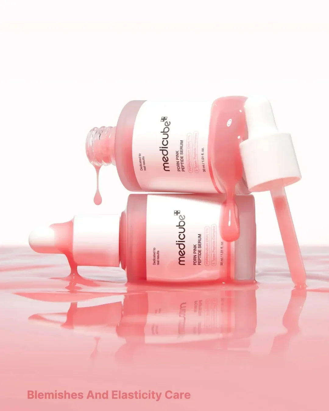 Two Medicube PDRN Pink Peptide Serum bottles with dropper on pink liquid surface for blemishes and elasticity care