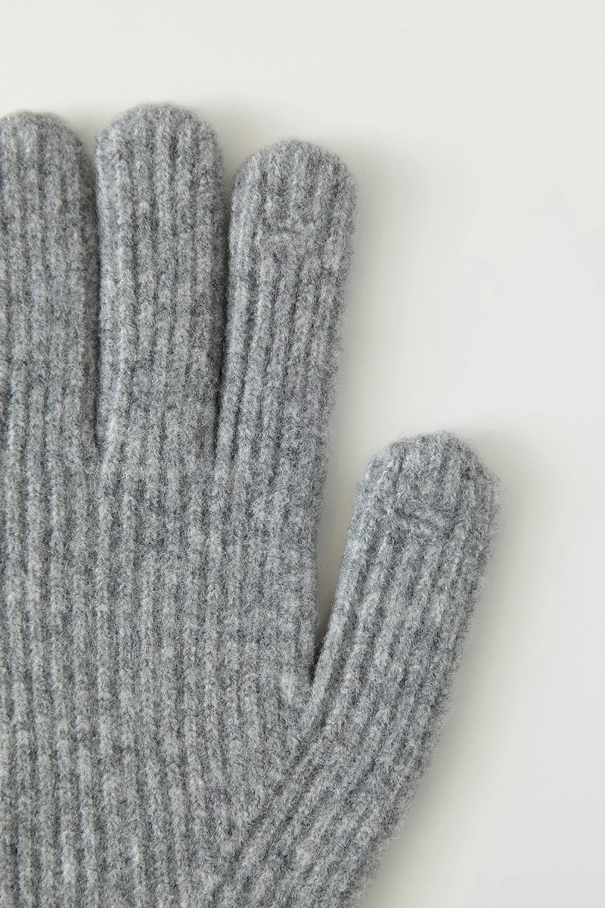 Close-up of gray knitted wool gloves showing textured ribbed pattern on fingers