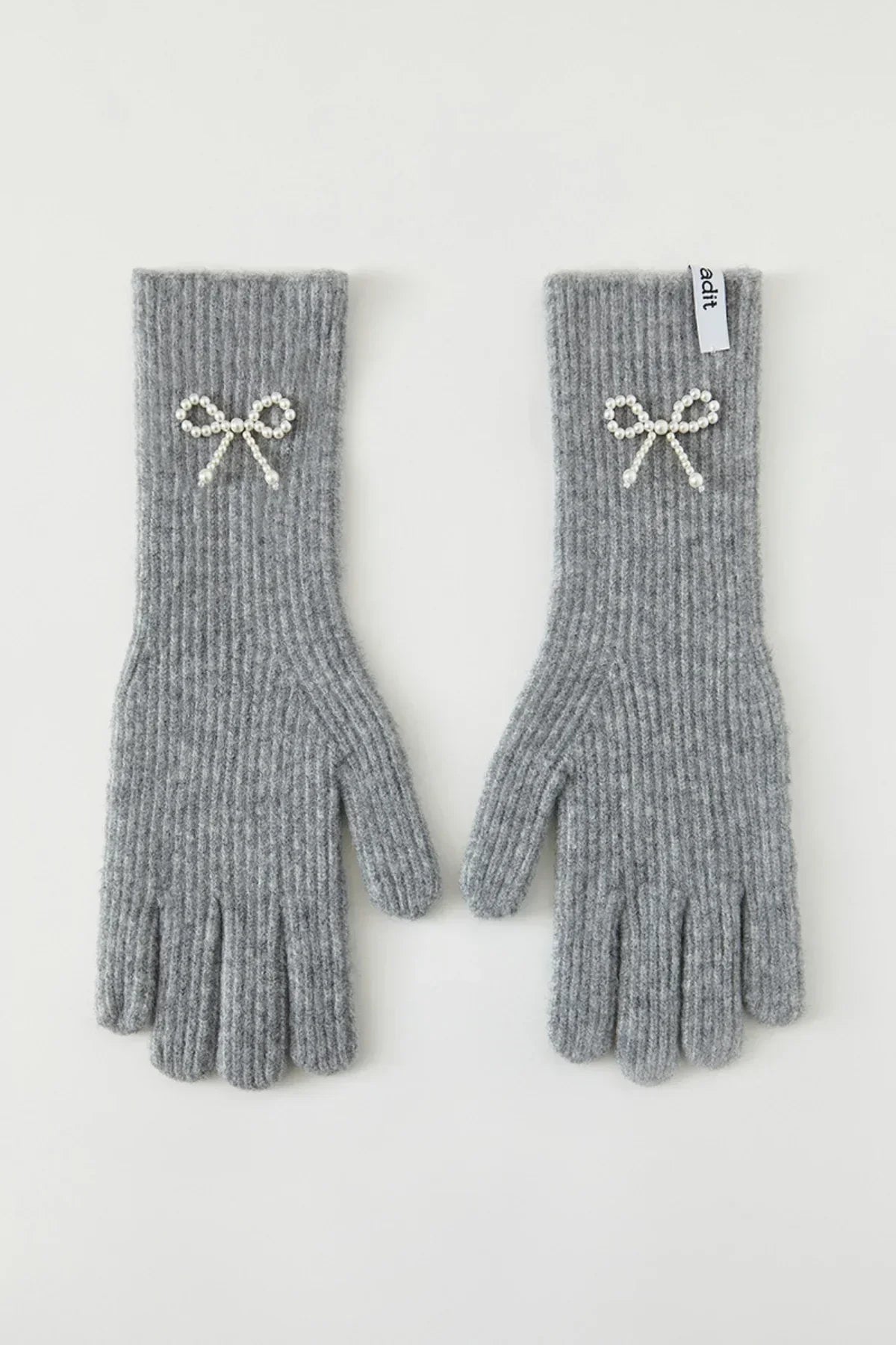 Gray ribbed knit gloves with pearl bow embellishments and a white adit brand tag
