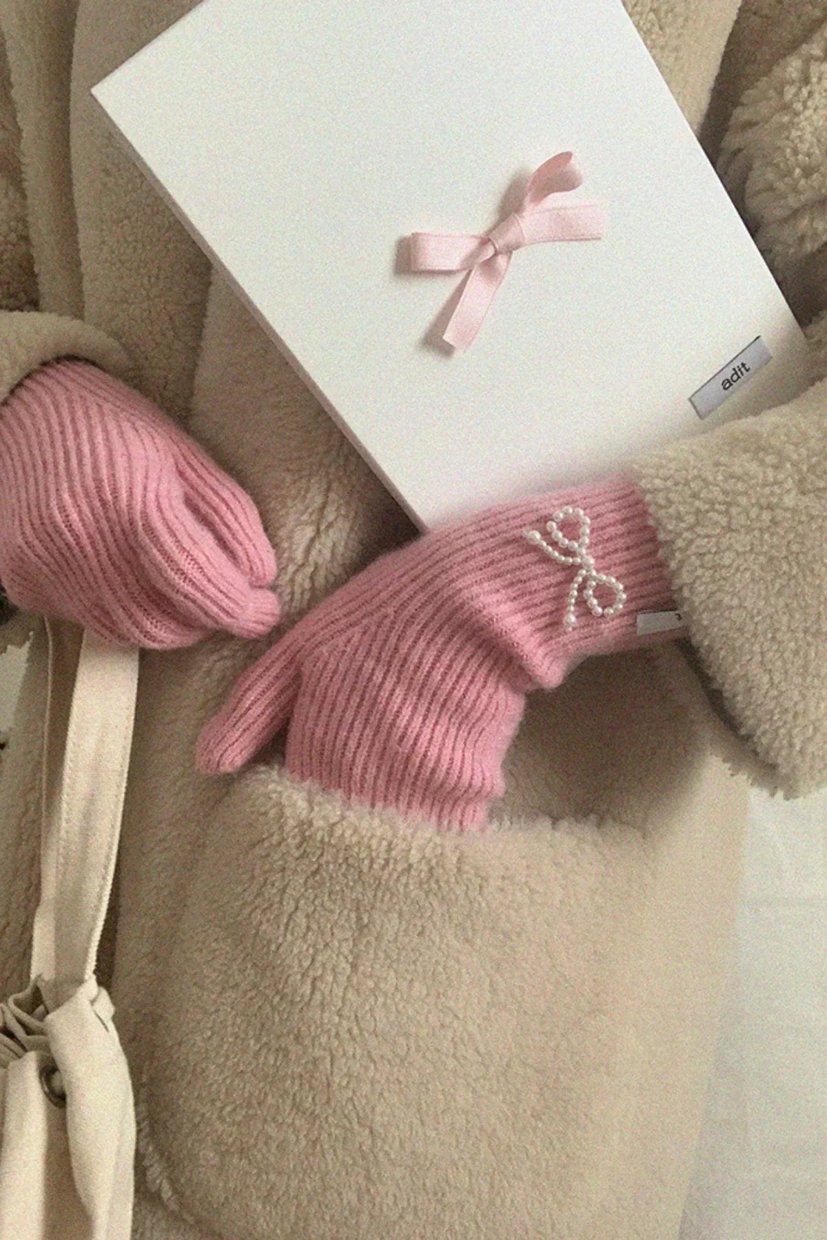 Pink knit gloves with pearl ribbon detail and matching hat in beige sherpa coat pocket