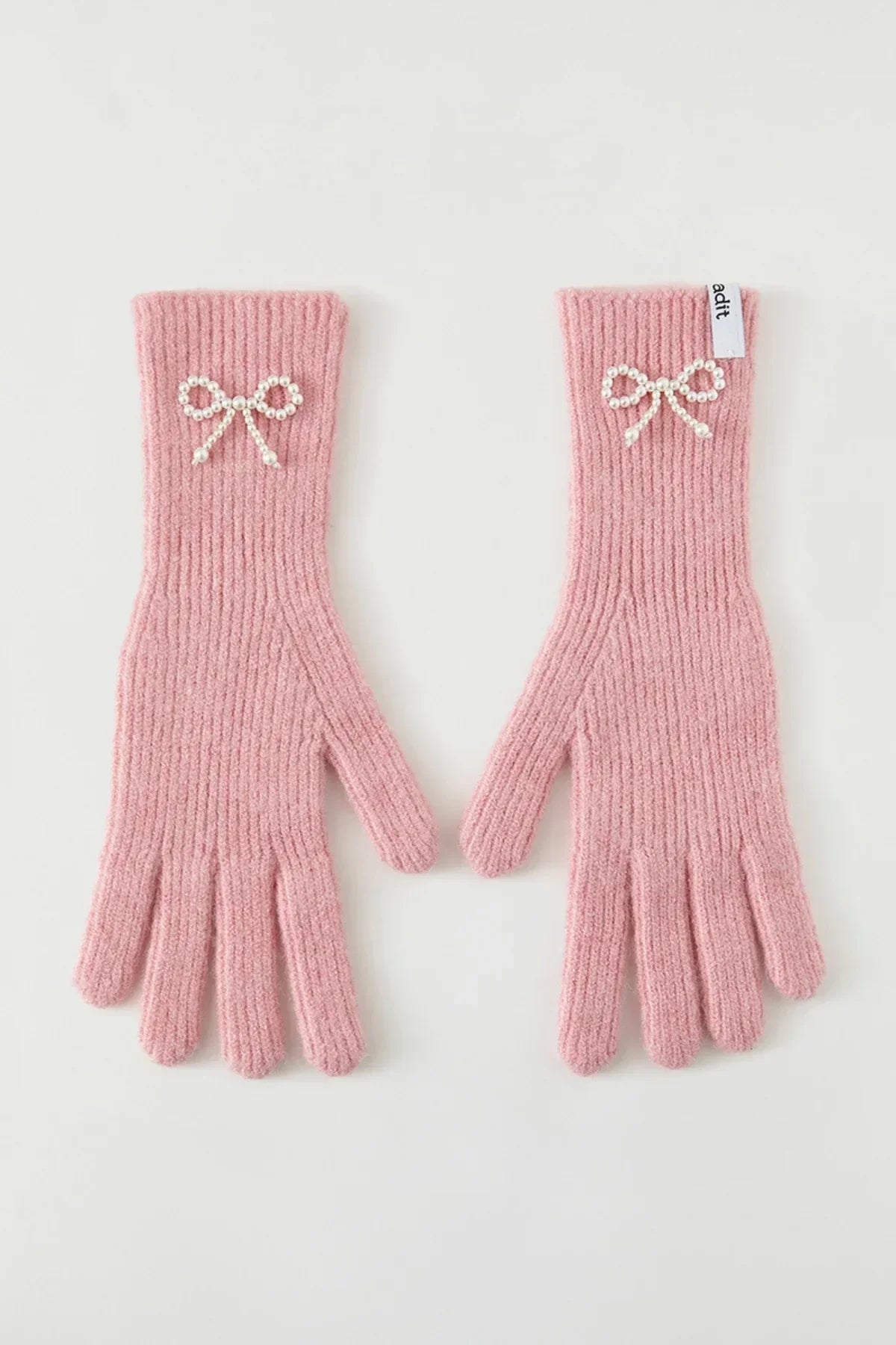 Pair of pink ribbed knit gloves with pearl bow embellishments, flat on white background