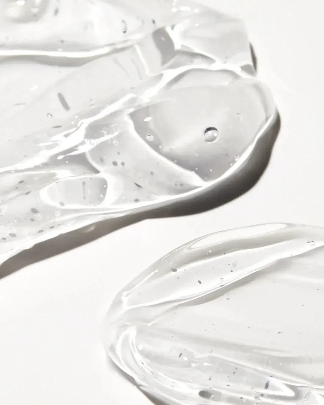 Close-up of clear gel texture with bubbles on white background, skincare product sample