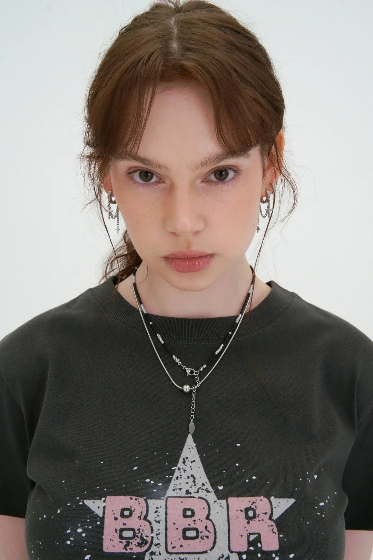 Close-up of woman wearing charcoal BBR star print t-shirt with layered silver and black beaded necklaces