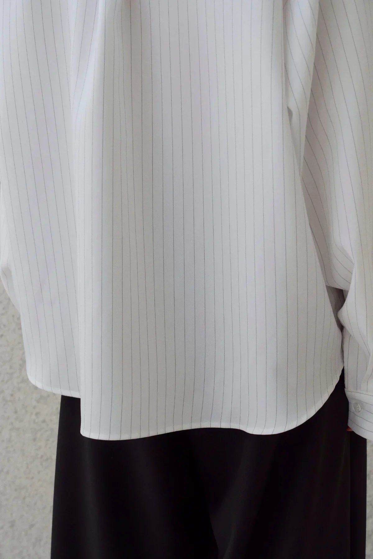 Close-up of a white pinstripe shirt paired with black pants on a person