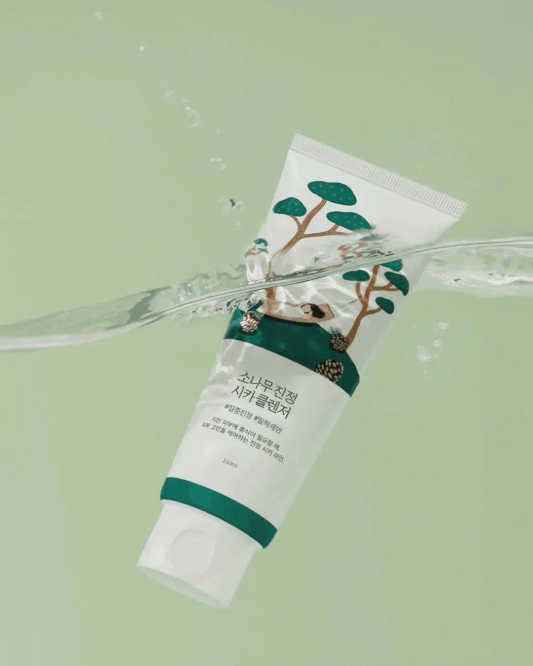 Pine Calming Cica Cleanser tube partially submerged in water against a light green backdrop